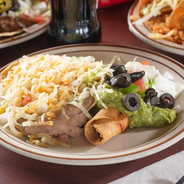 A Pancho Villa's combination plate with a taquito, refried beans, cheese, guacamole, and sour cream.